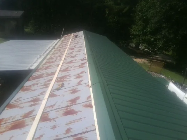 Old rusted panels beside newly installed green metal roofing — Wind Damage Roof Repair by Roofing Brothers in Westley