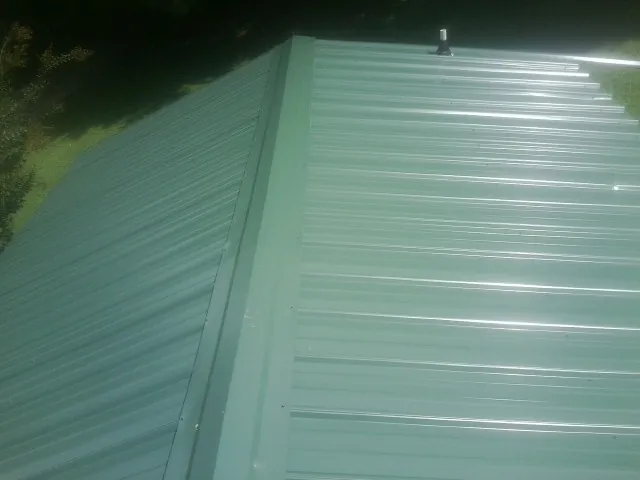 New green metal panels meeting at the ridge of a roof — Flat Roof Repair work by our crew in Westley