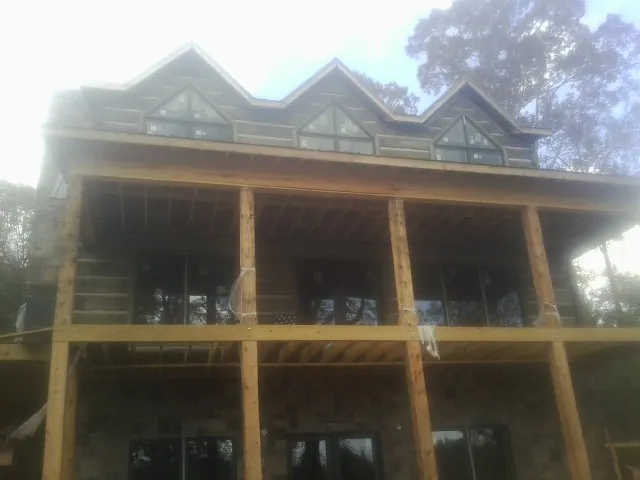 Dormers and porch framing on a large log home under construction — Roof Coating work by our crew in Westley