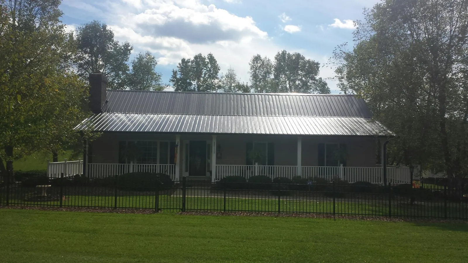 Gray metal roof on a brick ranch with a full width front porch — Gutter Guard Installation work by our crew in Westley