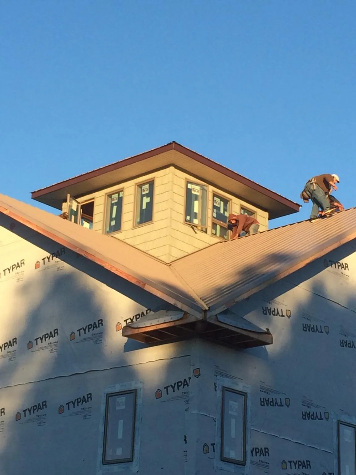 Roofers working around a rooftop cupola on a new metal roof at sunset — Roof Waterproofing in Westley by Roofing Brothers